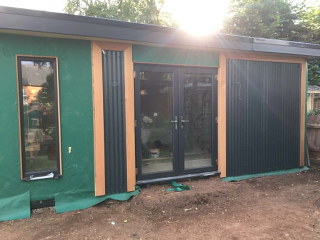 Finished garden room with dark cladding and full-height glazing